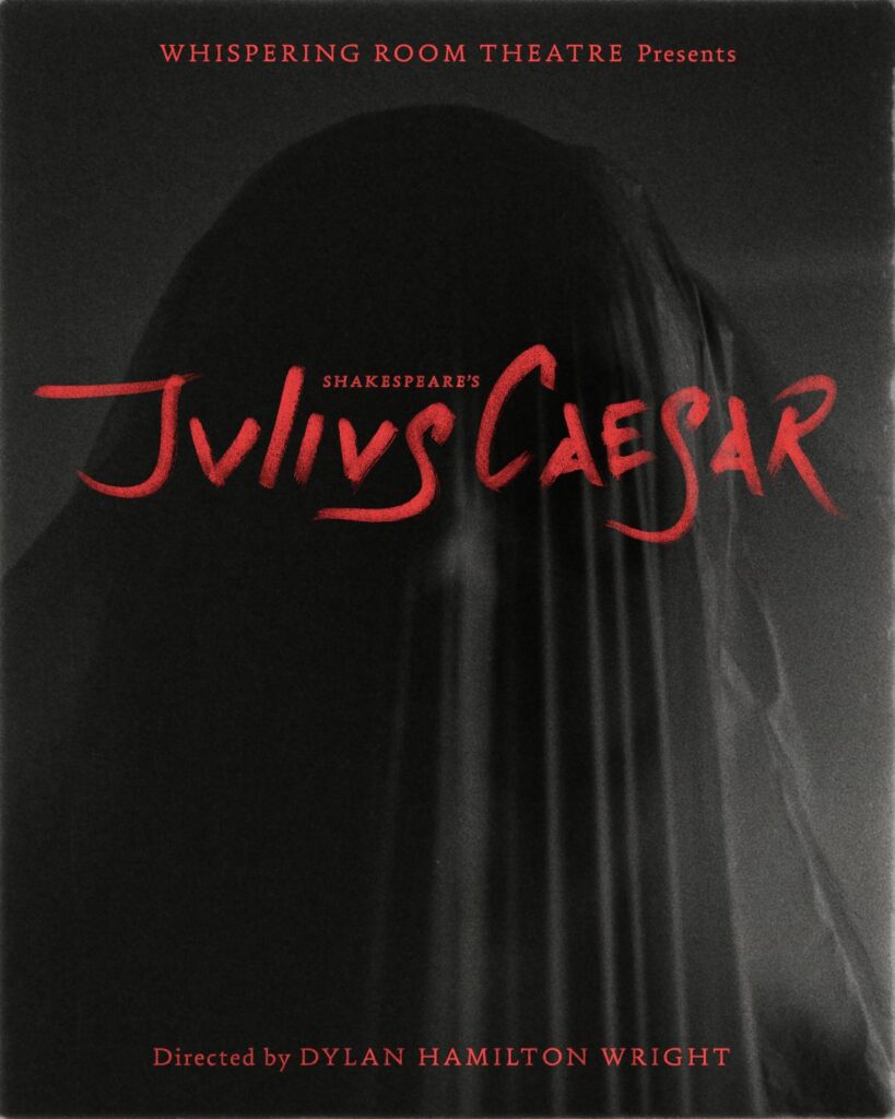 The image is a poster for a theatrical production of Shakespeare's "Julius Caesar." It features a dark, shadowy background with the faint outline of a human figure draped in a translucent fabric, creating an enigmatic and ghostly effect. The figure occupies the center of the image, adding an element of mystery and drama. The title "Julius Caesar" is prominently displayed in bold, stylized red text across the lower-middle portion of the image, drawing the viewer's attention. Above the title, the words "Whispering Room Theatre Presents" appear in smaller red text. Below, the phrase "Directed by Dylan Hamilton Wright" is written in red at the bottom.